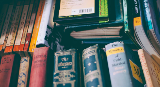 A collection of vintage old books in a box with the spines facing up