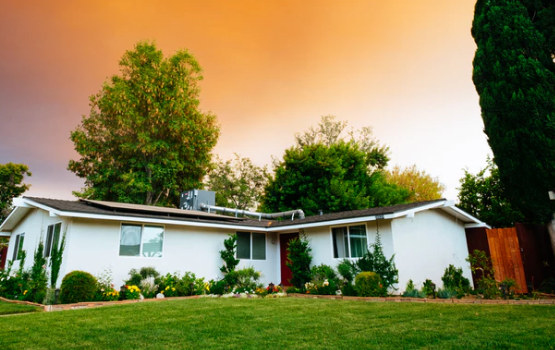 A small white house in a suburban neighborhood at sunset