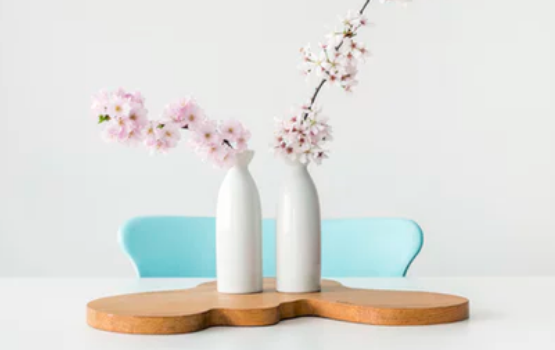 Two white vases with pink and white blossom branches on a table