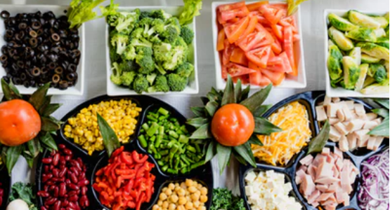 Colorful salad bar with greens, broccoli, black olives, peppers and more