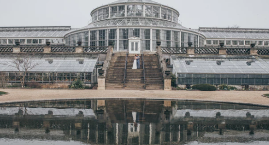 Newlyweds pose on staircase in front of Botanical Garden with lake in front