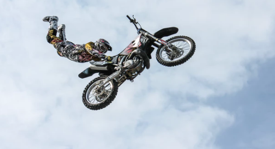 A motocross biker doing a handstand in the air on his motorcycle