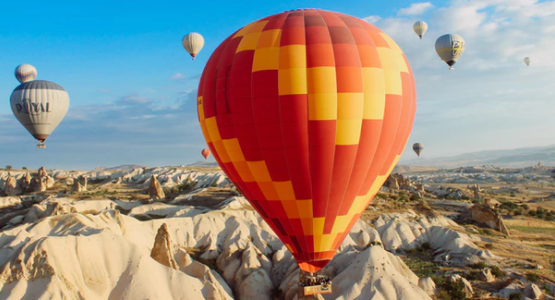 Colorful hot air balloons fly and float over a desert landscape